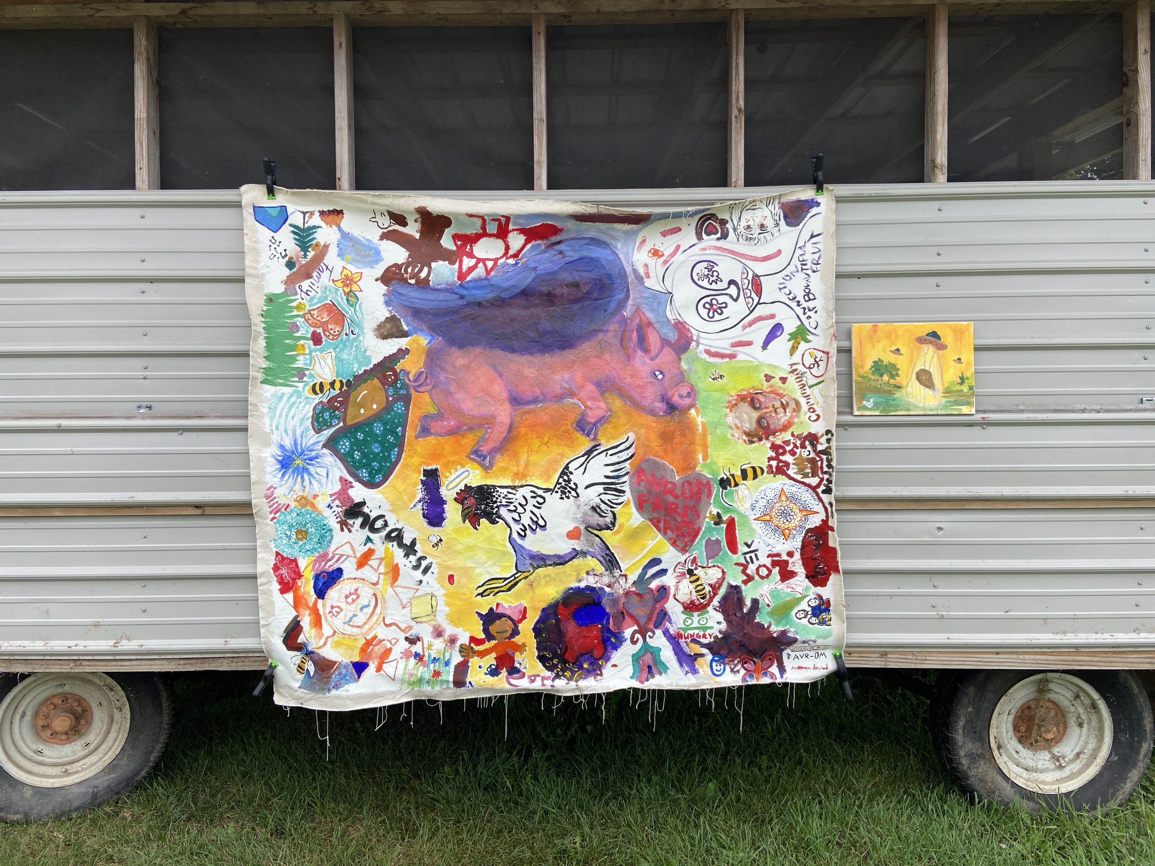 A colorful painting depicting a pig, a chicken, and other forms, painted by festival-goers at Avrom Farm Party.
